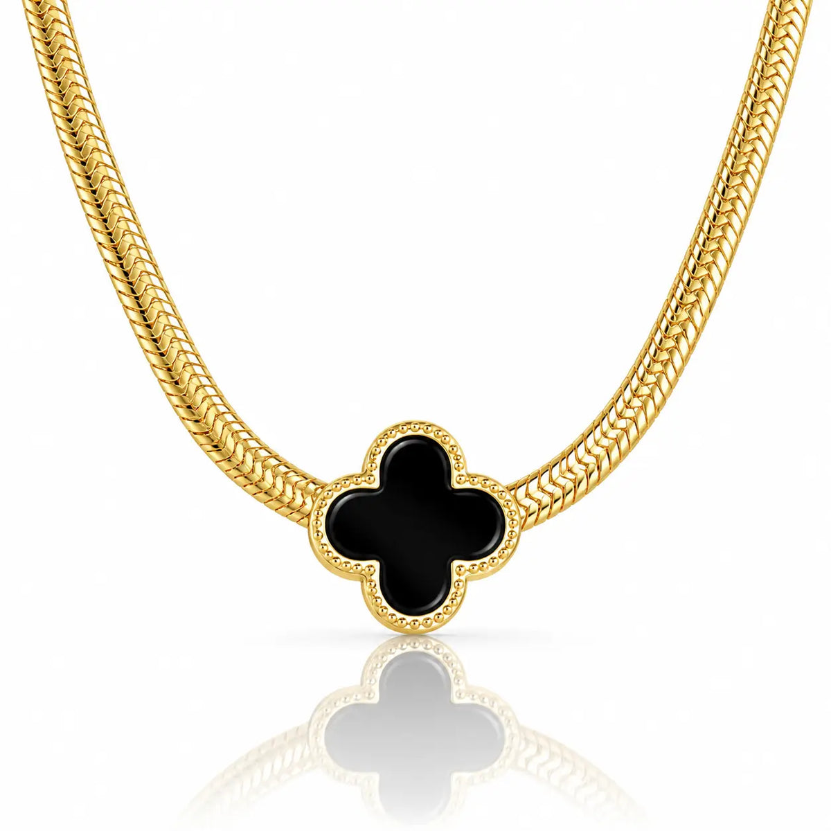 A gold chain necklace featuring a black four-leaf clover pendant with a textured gold border, displayed on a clean white background with a soft reflection below.