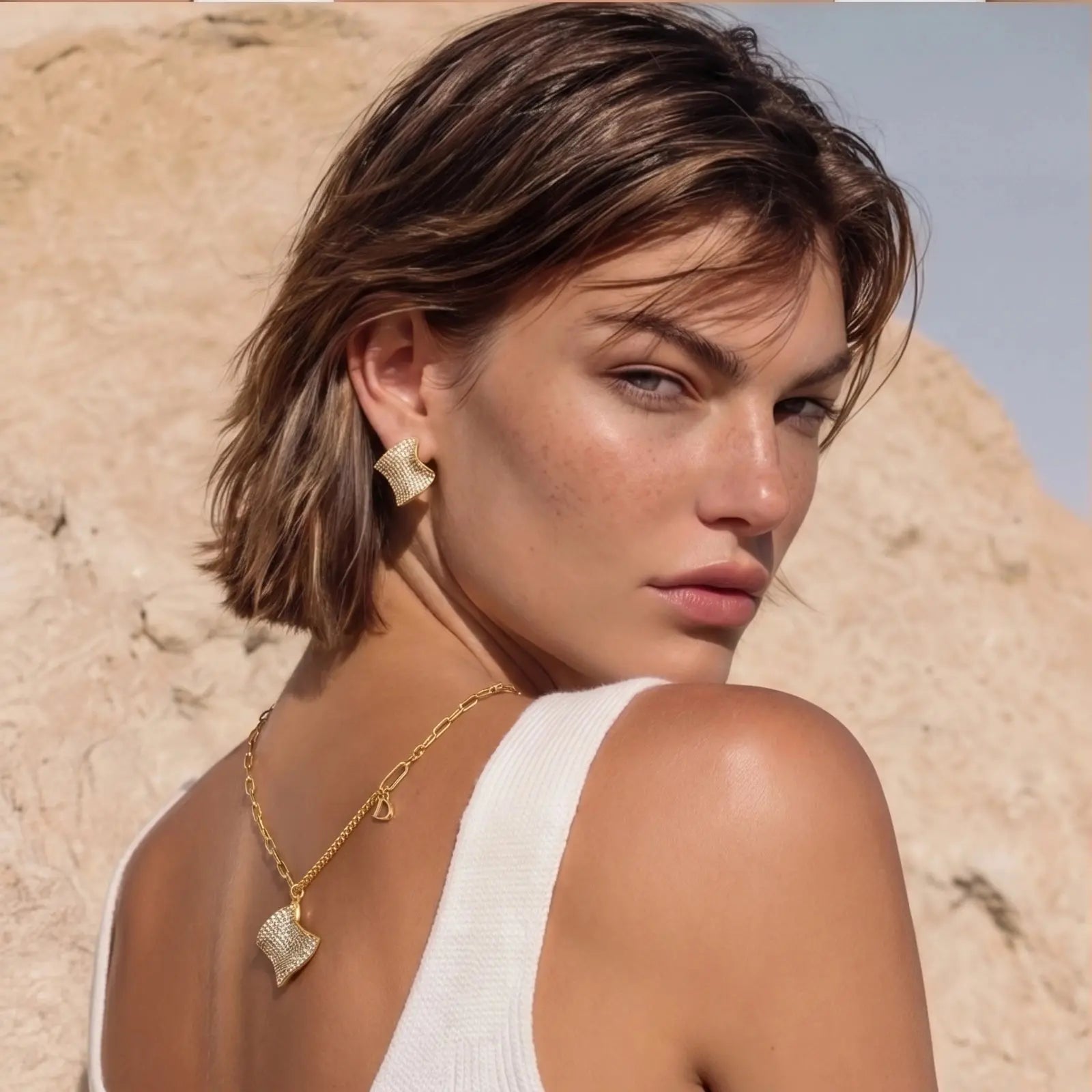 Woman wearing gold jewelry against a desert background