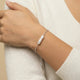 Woman wearing a silver bracelet with a baroque pearl charm on wrist, minimalist jewelry