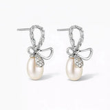 Silver bow earrings with pearl drops and crystal accents on a white background