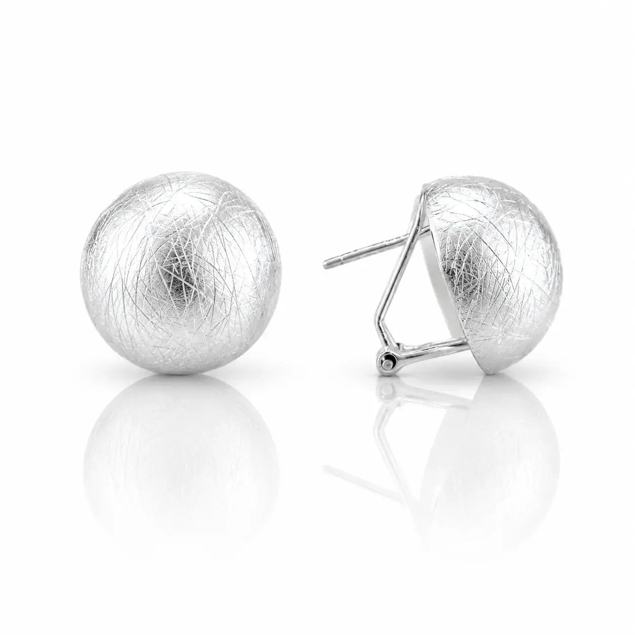 A pair of textured silver ball stud earrings, one shown from the front and the other from the side displaying the post and butterfly back, on a reflective white surface.