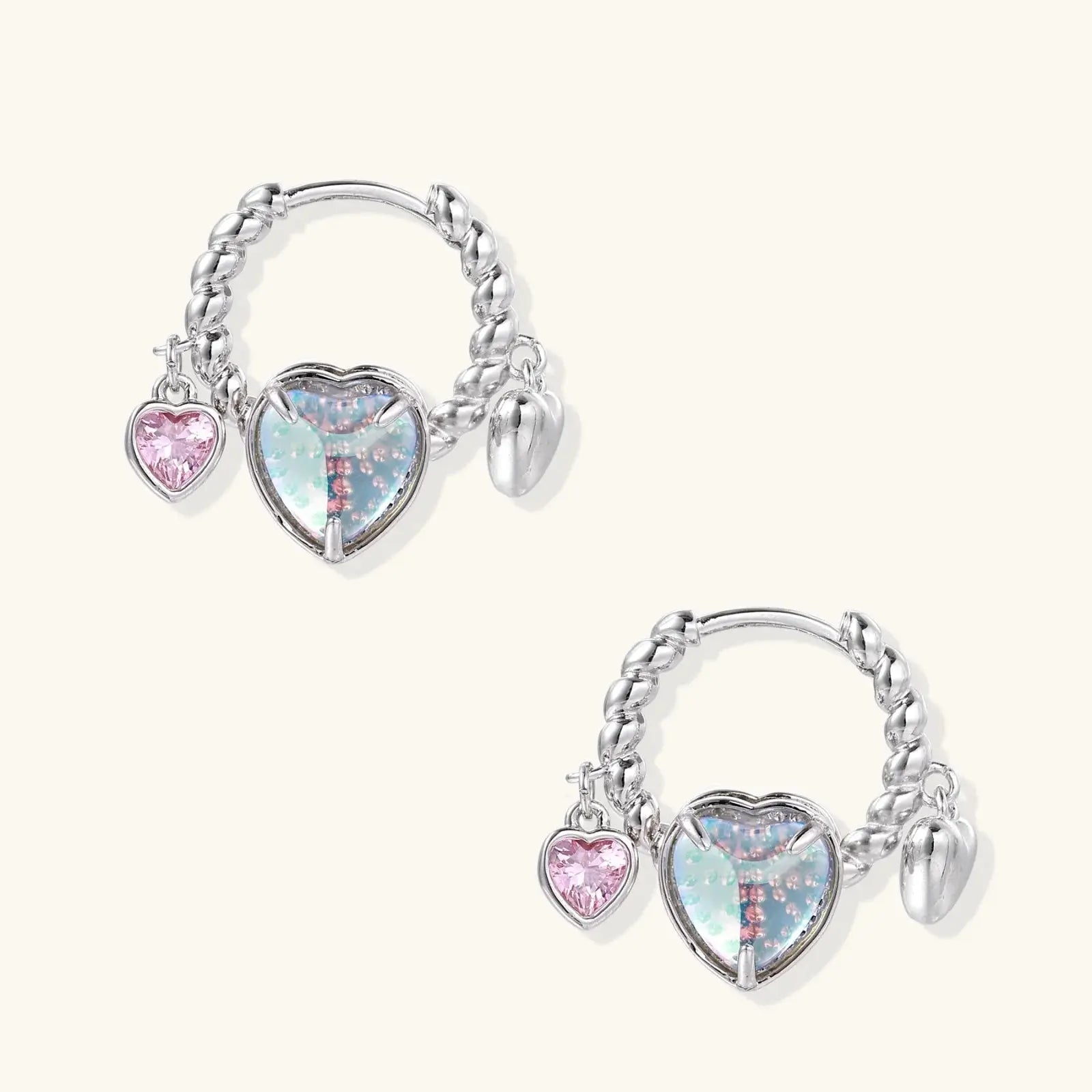Pair of silver hoop earrings with heart-shaped charms on a white background