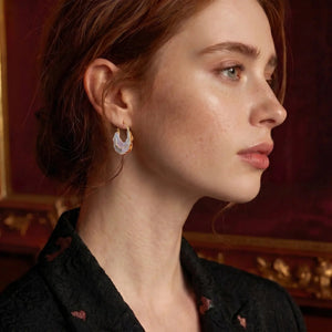 Close-up of a woman wearing earrings with a red background