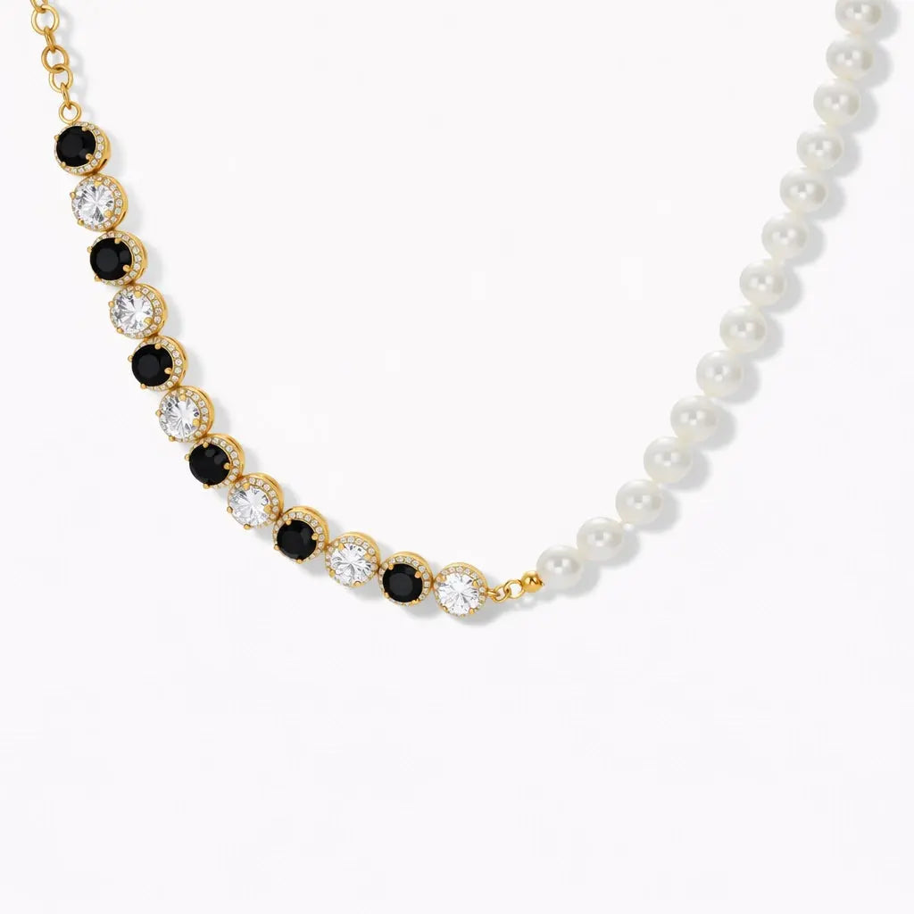 Gold necklace with alternating black and clear stones, pearl strand detail, on white background.