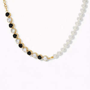 Gold necklace with alternating black and clear stones, pearl strand detail, on white background.