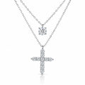 A silver-tone double-strand necklace featuring a small round solitaire pendant and a larger cross pendant paved with small clear stones, shown on a white background.