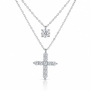 A silver-tone double-strand necklace featuring a small round solitaire pendant and a larger cross pendant paved with small clear stones, shown on a white background.