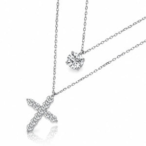 Silver-toned cross pendant necklace and matching solitaire necklace set with clear gemstones, displayed on a clean white background with a soft reflection.