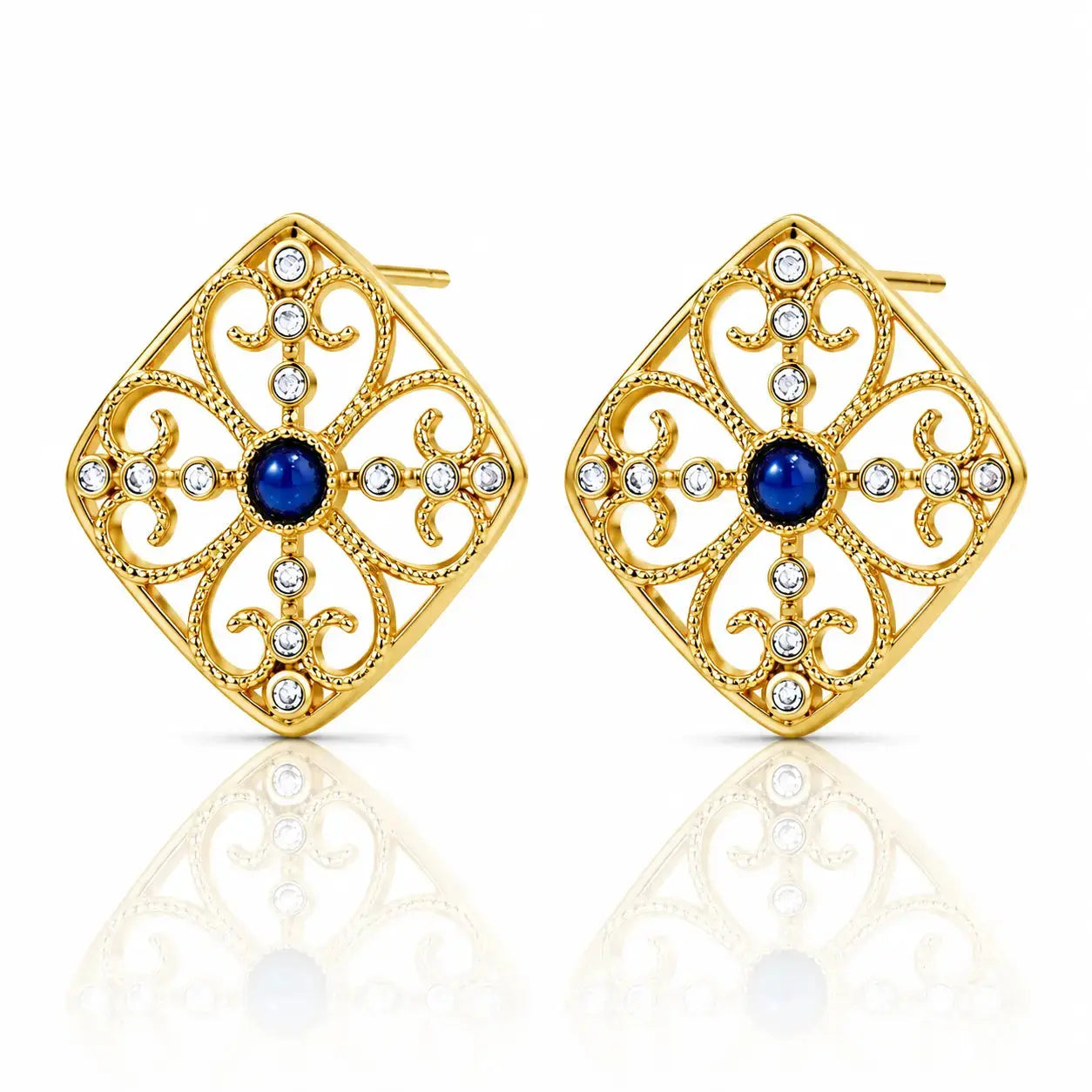 A pair of gold filigree stud earrings with a central deep blue gemstone and small clear rhinestones, displayed on a clean white background with a soft reflection below.