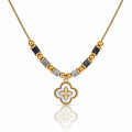 A gold-plated necklace featuring a central white enamel quatrefoil pendant with a gold border, flanked by alternating gold and black faceted beads on a white background.