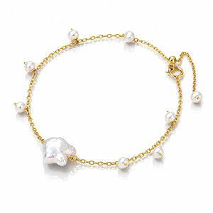 A delicate gold chain anklet featuring a large baroque pearl and several smaller white freshwater pearls, displayed on a clean white background.
