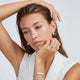 Woman wearing silver jewelry including earrings, ring, and bracelet against a white background