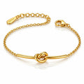 A gold chain bracelet with a central bar and knot design, featuring a lobster clasp and an adjustable chain extender engraved with the brand name 'TOKYO'.