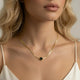 Woman wearing elegant 18K gold necklace with black four-leaf clover pendant