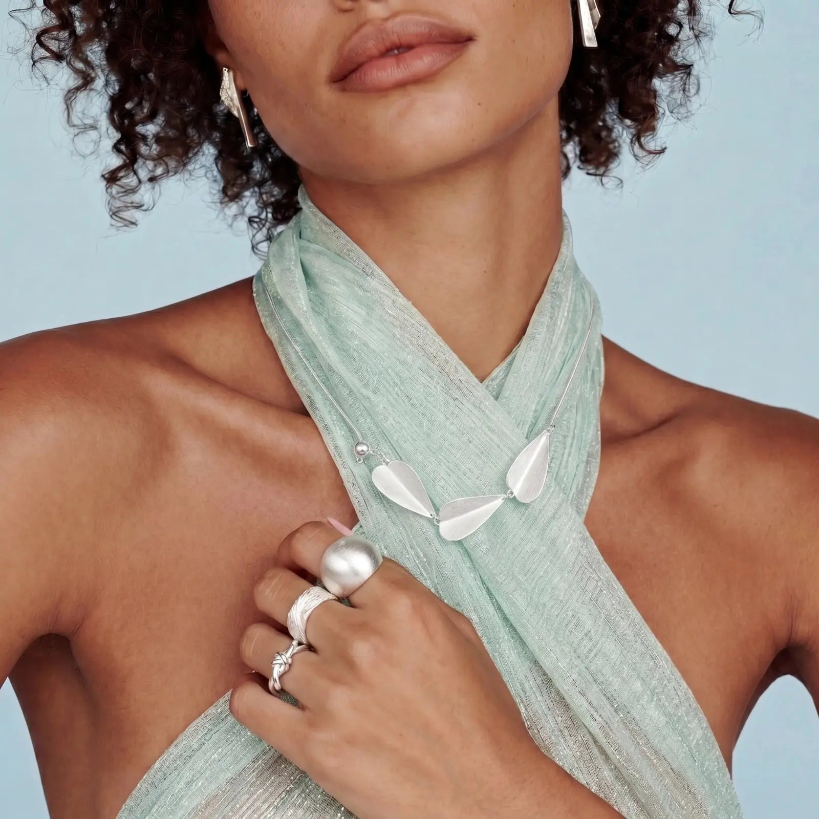 Woman wearing a light green scarf with a plain background