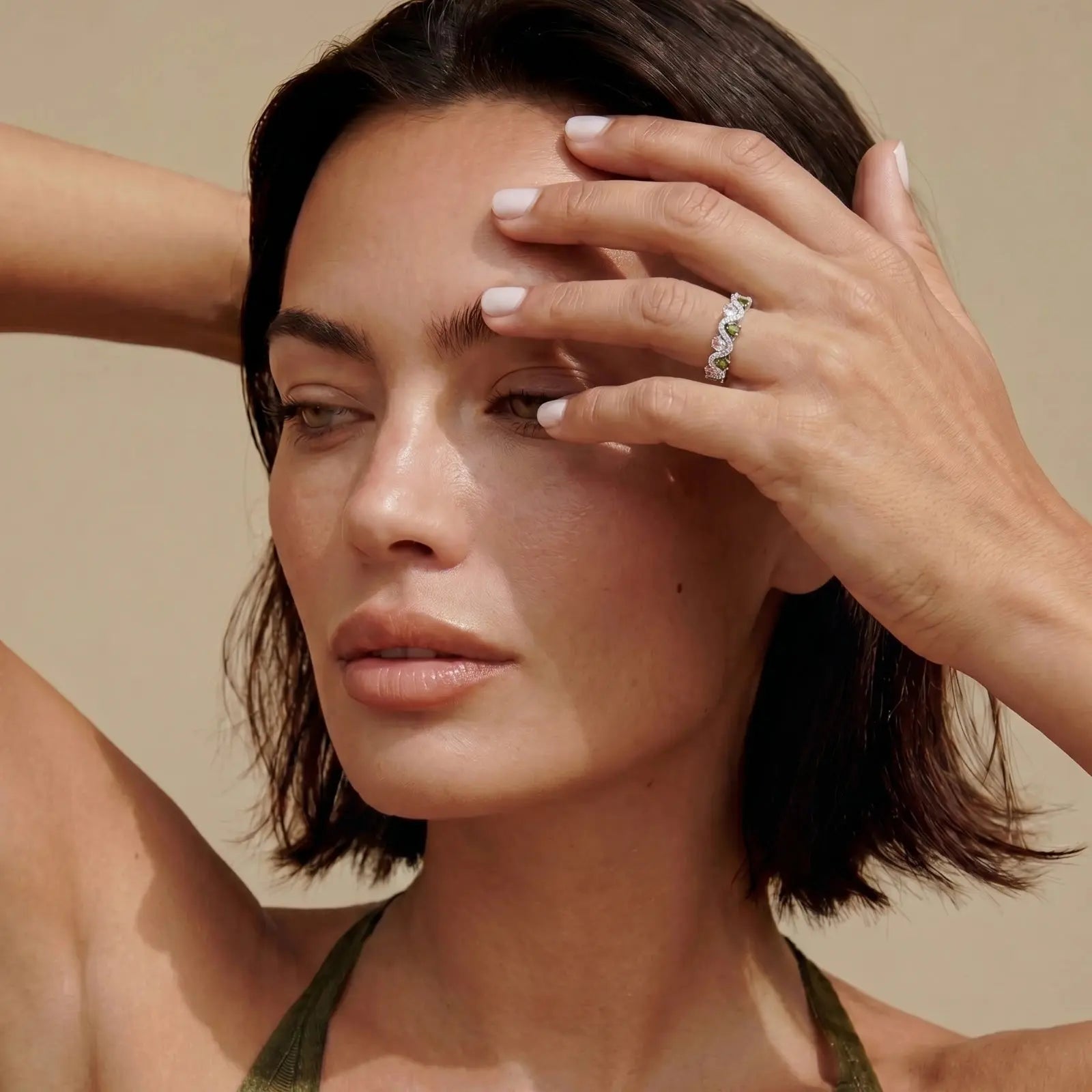 Woman with a ring on her finger against a beige background