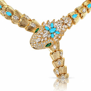 A gold-tone snake necklace pavé-set with clear diamonds and accented with turquoise and green emerald stones, displayed on a clean white background with a soft reflection.