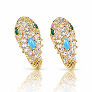 A pair of gold huggie hoop earrings adorned with clear pavé stones, a central light blue oval cabochon, two green oval stones, and a ribbed gold end, shown on a white background with a soft reflection.