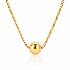 A gold box chain necklace with a polished spherical bead pendant, displayed against a clean white background with a soft reflection below.