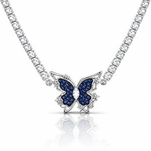 A silver-tone butterfly pendant necklace featuring dark blue pavé-set wings and a clear central stone, suspended from a sparkling silver chain on a white background with a soft reflection.