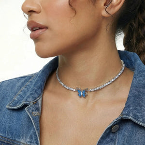 Woman wearing a sparkling butterfly necklace with blue gemstone pendant on a crystal chain