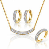 Gold jewelry set featuring a necklace, hoop earrings, and a ring, each adorned with rows of clear pavé stones on a white background with soft reflections.