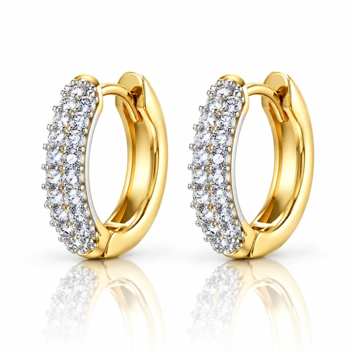 A pair of gold huggie hoop earrings set with clear pavé gemstones on a clean white background with a soft reflection below.