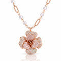 Rose gold floral pendant necklace with a flower-shaped centerpiece paved with clear stones and a chain featuring white pearls and textured rose gold links, shown on a white background with a soft reflection.