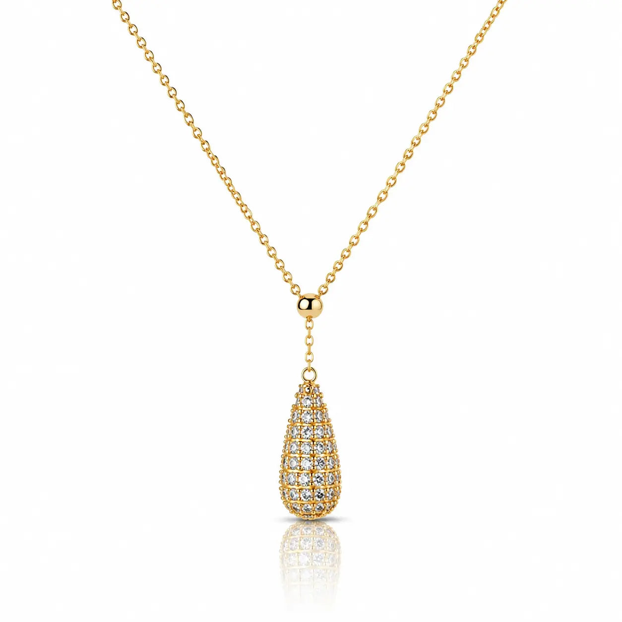 A gold chain necklace with a teardrop-shaped pendant paved with small clear stones, shown on a clean white background with a soft reflection below.