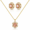 Gold jewelry set featuring a pendant necklace and matching stud earrings with oval peach-pink center stones surrounded by clear crystals on a white background.