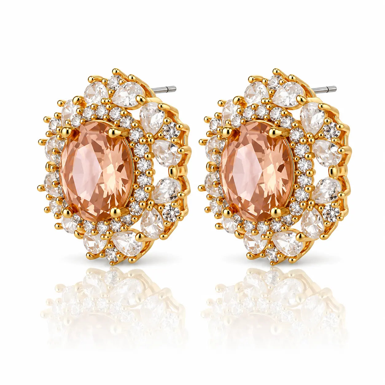 A pair of gold-plated oval stud earrings featuring a central peach-colored marquise-cut gemstone surrounded by a double halo of clear round and oval cubic zirconia stones, shown on a white background with a soft reflection.