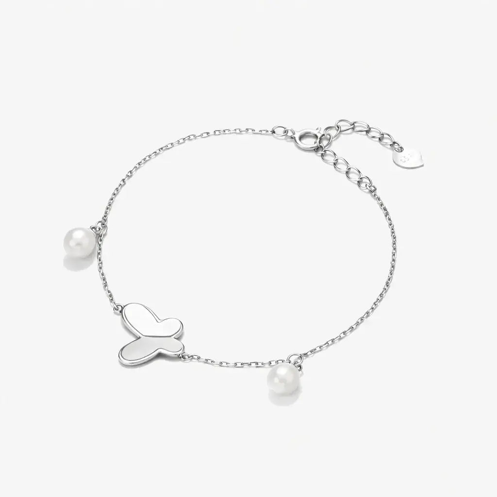 Sterling silver bracelet with butterfly charm and two freshwater pearls on white background