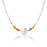 A delicate white pearl beaded necklace featuring a central irregular white pearl, accented by gold-toned beads, a small coral-red bead, and a light blue-green bead on a white background.