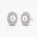 Elegant oval pearl stud earrings with double halo of sparkling pave stones on white background.