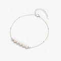 Delicate silver chain bracelet with five white pearls and adjustable clasp on white background