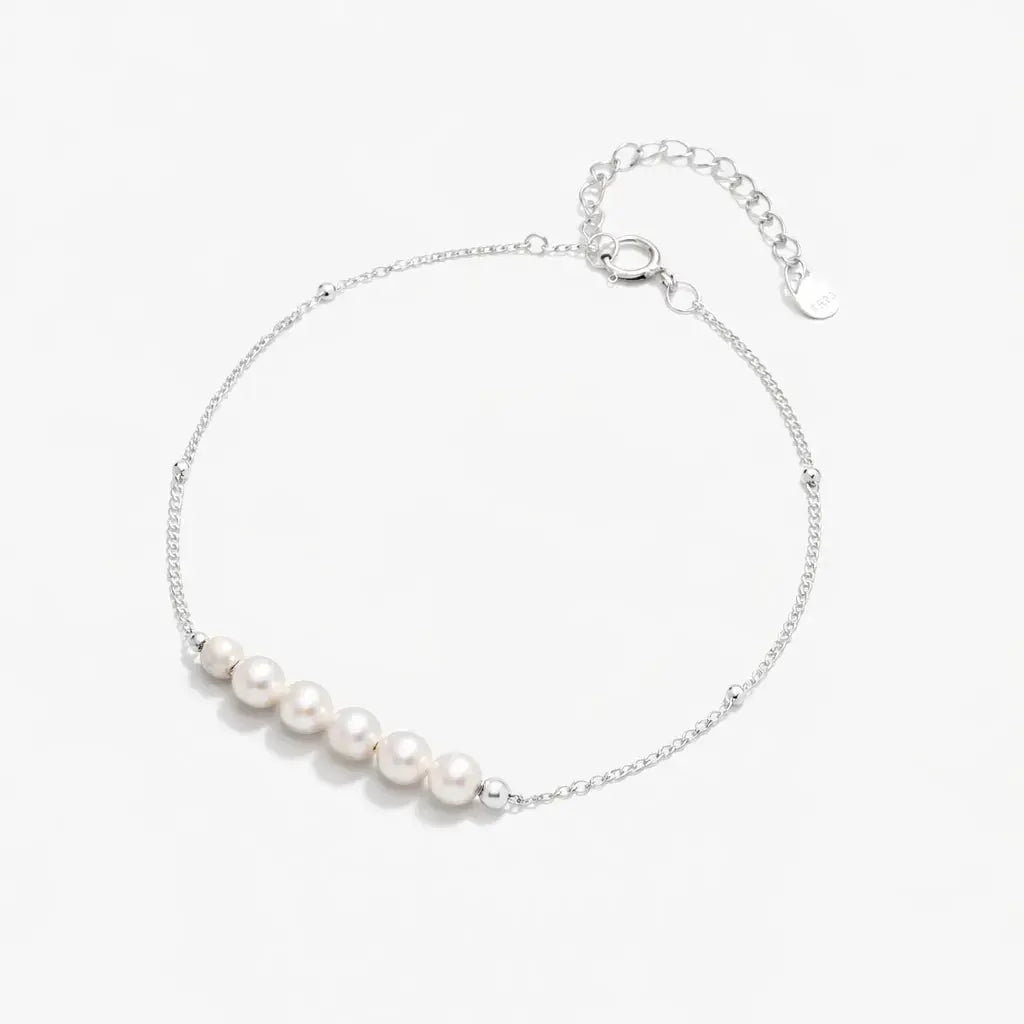 Delicate silver chain bracelet with five white pearls and adjustable clasp on white background