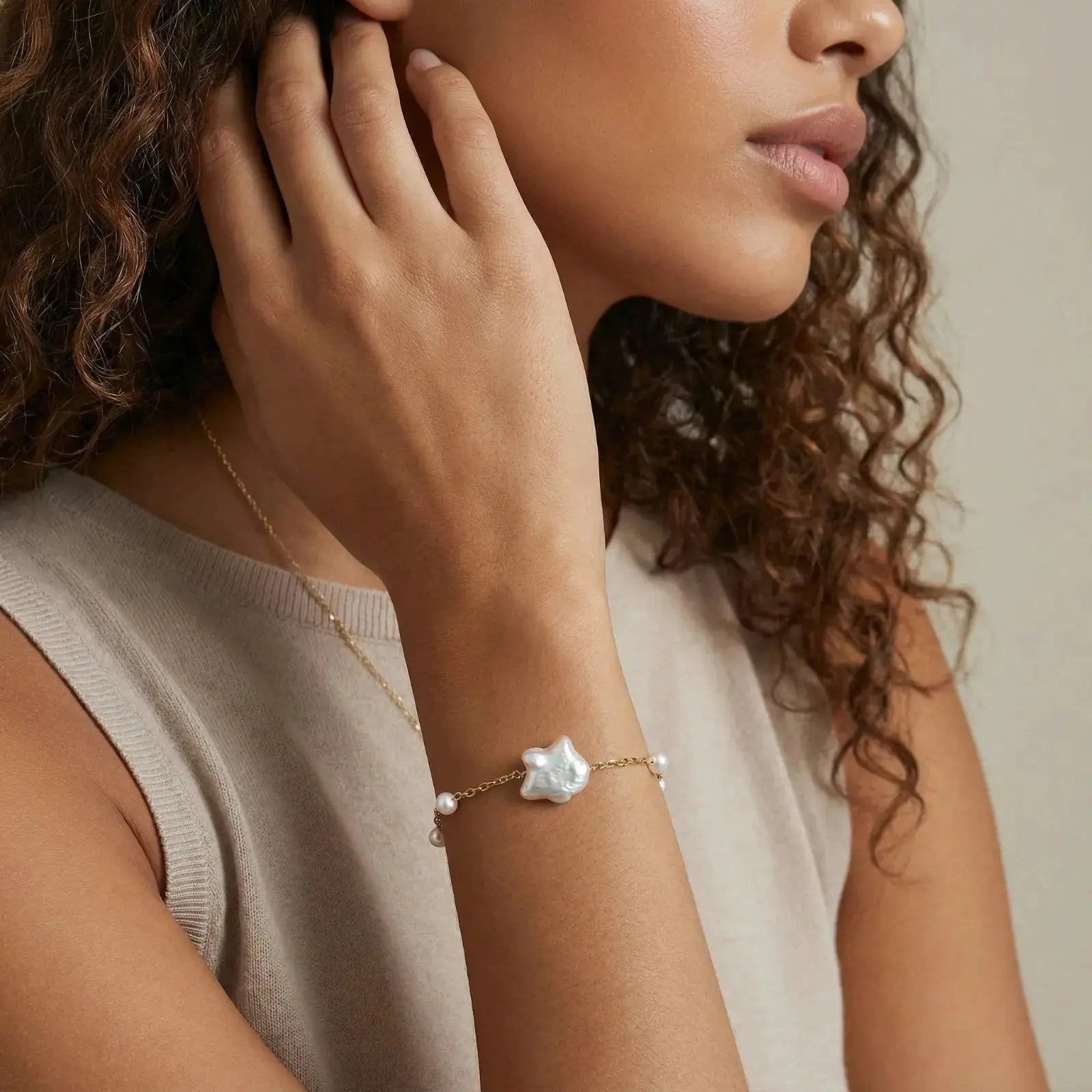 Woman wearing a gold chain bracelet with baroque pearl centerpiece and accent pearls