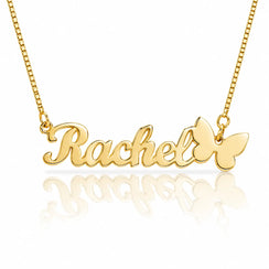 A gold nameplate necklace spelling 'Rachel' with a butterfly charm at the end, shown on a white background with a soft reflection below.