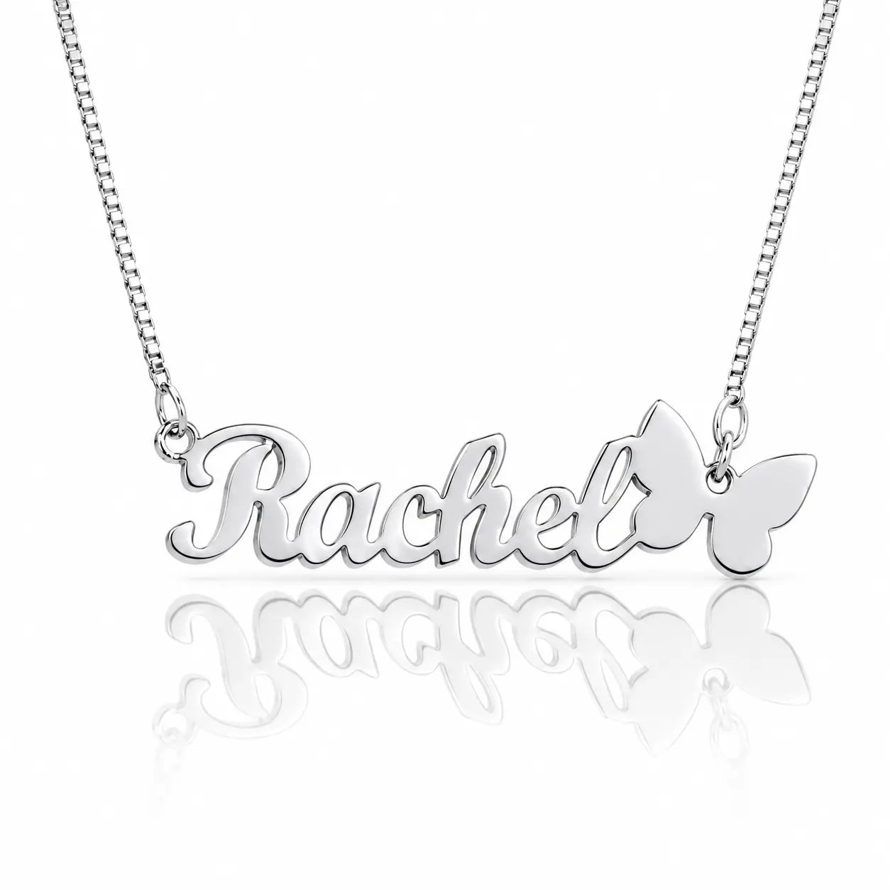 A silver nameplate necklace spelling 'Rachel' in cursive, with a butterfly pendant on the right side, suspended from a silver chain against a white background with a soft reflection below.