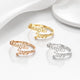 Three personalized name rings reading 'Annetta Jose' in gold, rose gold, and silver, arranged on a clean white reflective surface with soft draped fabric in the background.