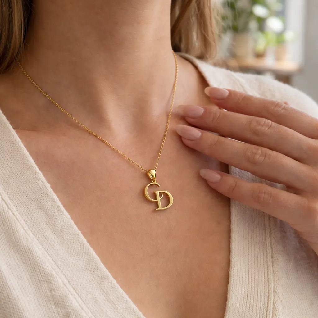 Gold necklace with a pendant worn by a person, with a blurred indoor background.