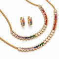 Gold jewelry set featuring a necklace, matching earrings, and a bracelet, each adorned with baguette-cut rainbow-colored stones and clear pavé accents on a white background.