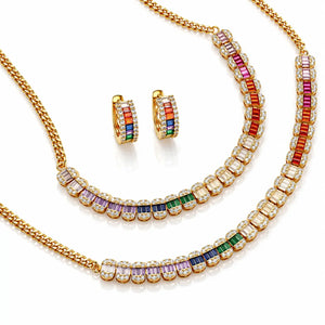 Gold jewelry set featuring a necklace, matching earrings, and a bracelet, each adorned with baguette-cut rainbow-colored stones and clear pavé accents on a white background.