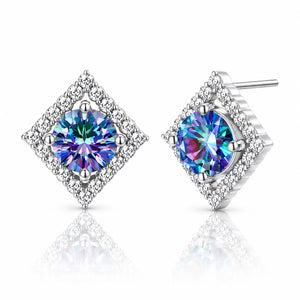 A pair of diamond-shaped stud earrings featuring iridescent blue and purple center stones surrounded by a halo of small clear stones, set in silver-toned metal on a white background with a soft reflection.