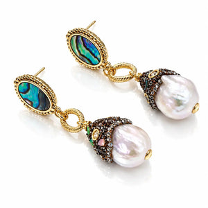 A pair of gold drop earrings featuring oval iridescent abalone shell inlays and large baroque pearls, accented with dark brown and green gemstones on a white background.