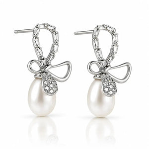 A pair of silver drop earrings featuring a bow-shaped setting with pavé-set clear stones and a dangling white pearl, shown on a clean white background with a soft reflection below.