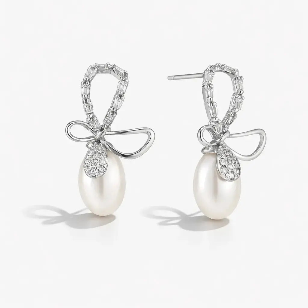 Pearl earrings with bow and crystal details on a white background