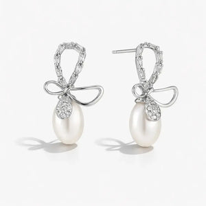 Pearl earrings with bow and crystal details on a white background