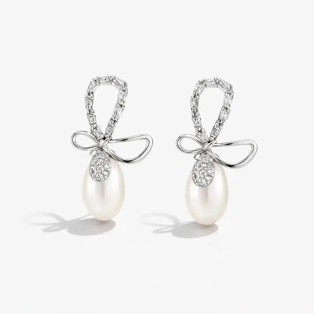 Pair of pearl earrings with bow designs on a white background