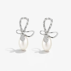 Pair of pearl earrings with bow designs on a white background